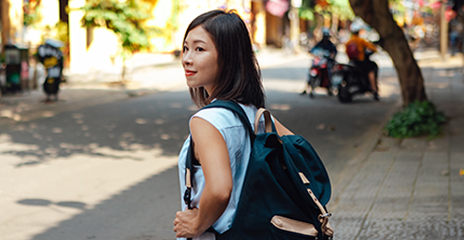 年轻的亚裔女性背着包在街上行走