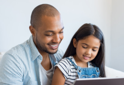 年轻的父亲和女儿微笑看着平板电脑