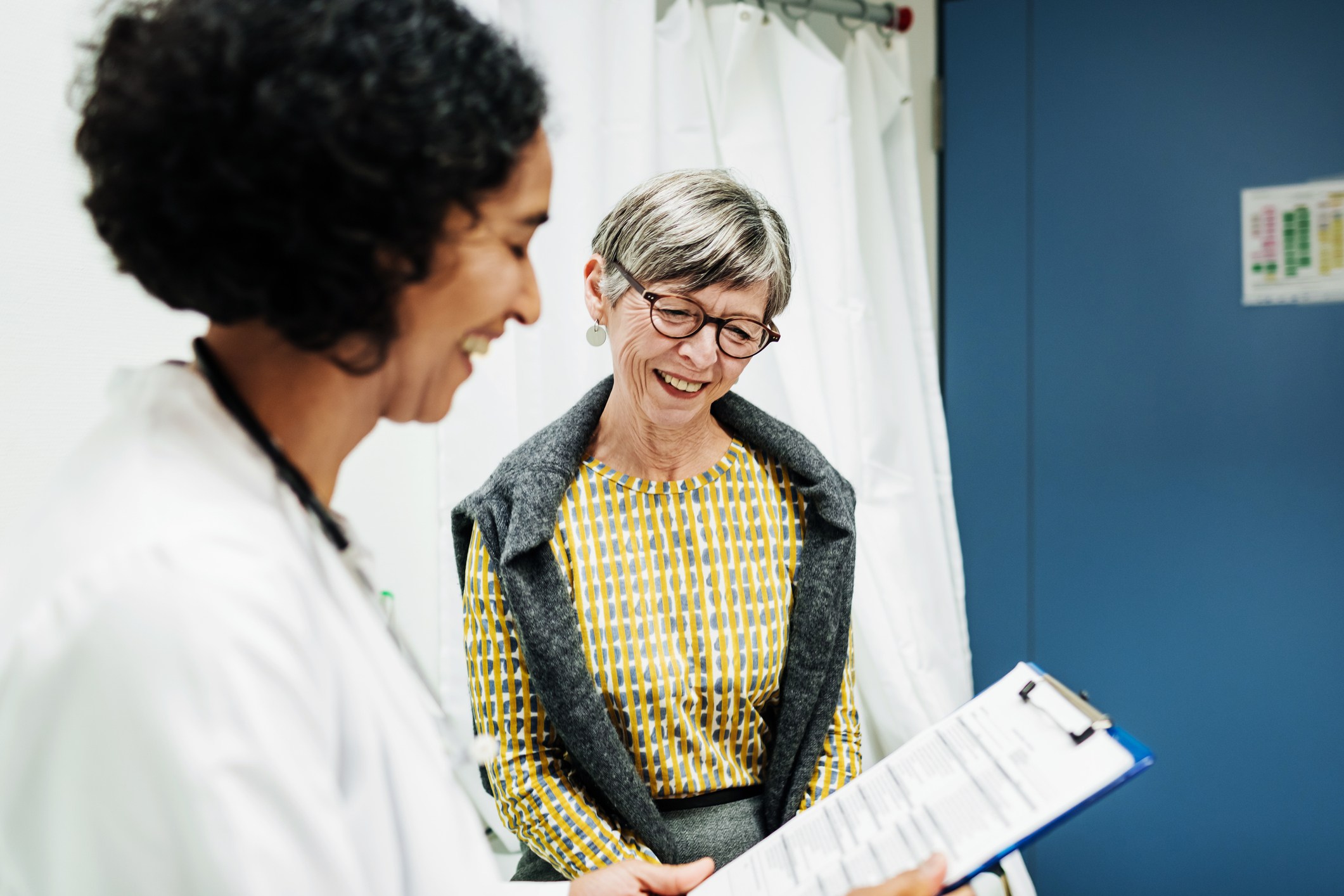一位临床医生在医院查看一位老年患者的一些测试结果。