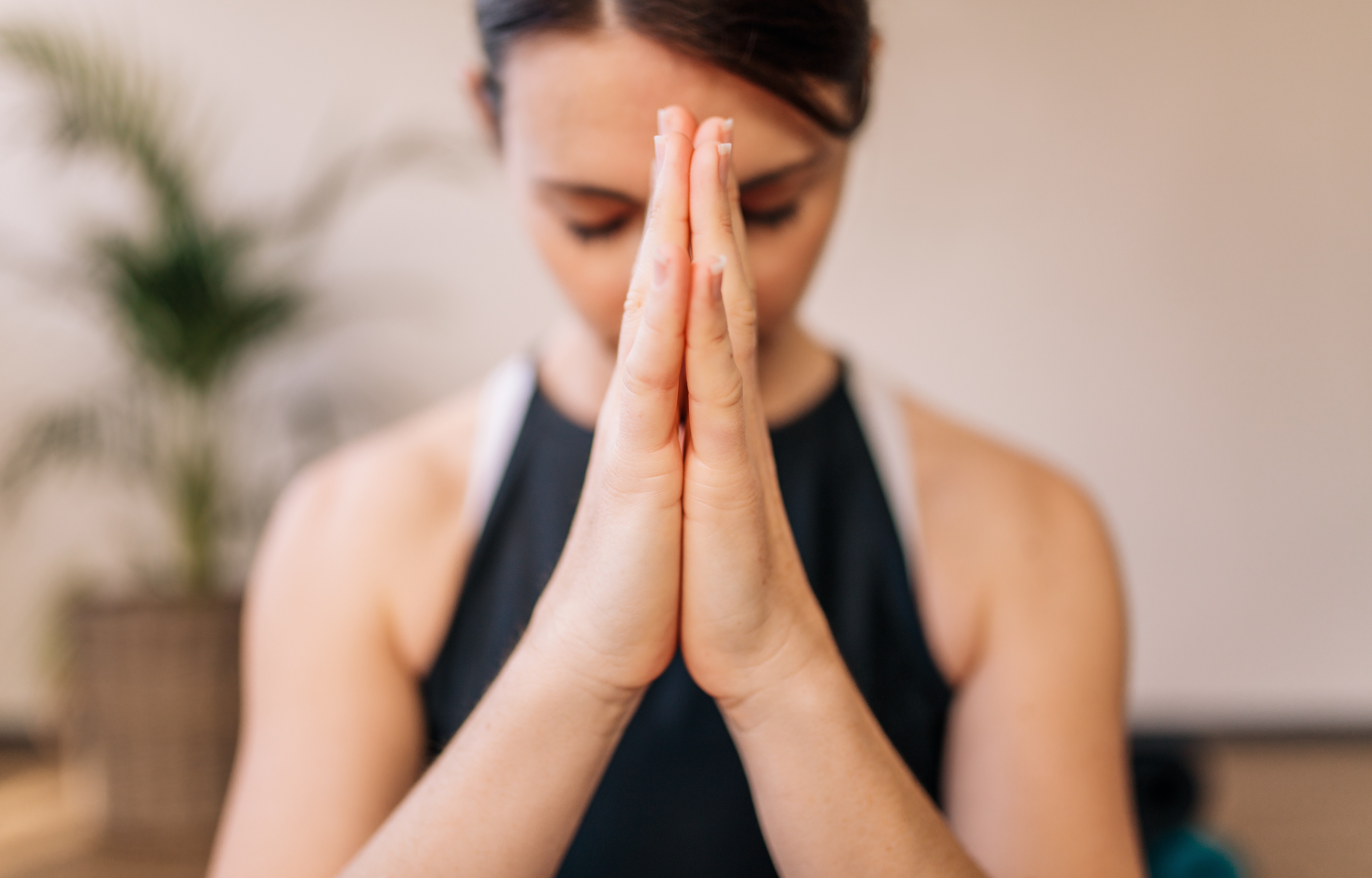 双手合十的女性的特写。双手合十在室内冥想的女性。合十礼瑜伽姿势，冥想，呼吸和放松。