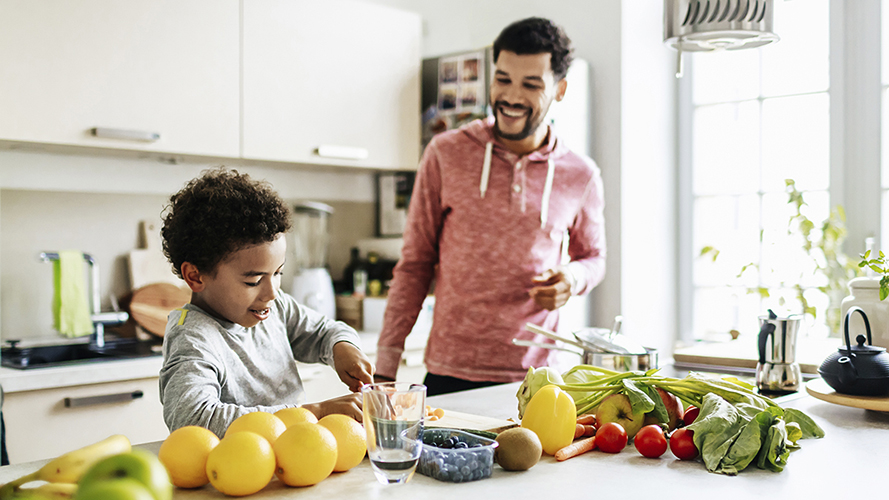孩子和他的父亲在厨房里。他们在用蔬菜制作健康的食物。