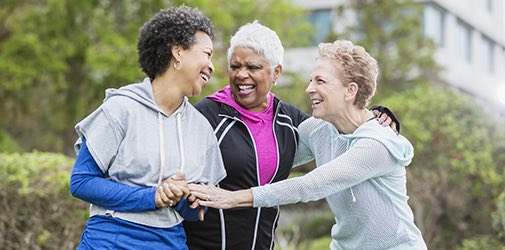 三名多种族女性穿着连帽运动衫，一起在城市里闲逛，散步时有说有笑。黑头发的女性 50 多岁，她的年长的朋友 60 多岁。